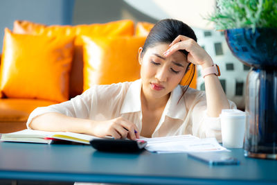 Young woman using mobile phone at table