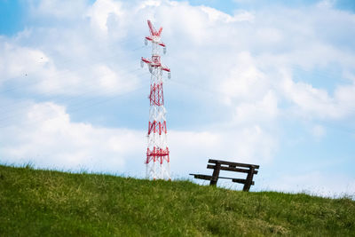 Low angle view of communications tower on field against sky