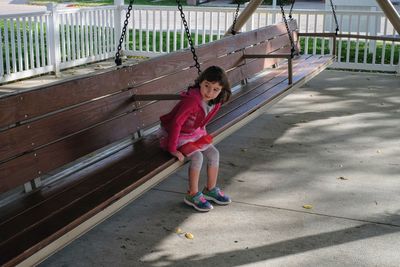 Girl sitting on large swing at park