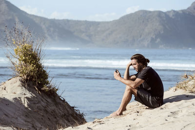 Man using smartphone on beach