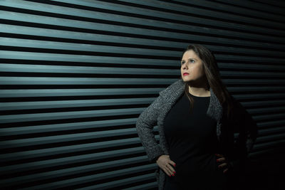 Young woman standing against wall