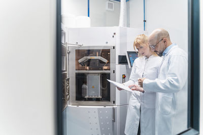 Two technicians wearing lab coats looking at plan