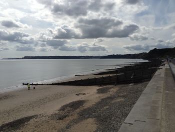 Scenic view of beach against cloudy sky