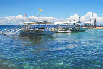 Boats moored in sea against blue sky