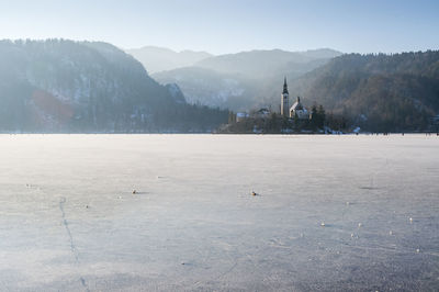 Scenic view of frozen lake bled by mountain against sky