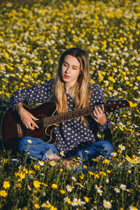 Beautiful young woman with yellow flower in field
