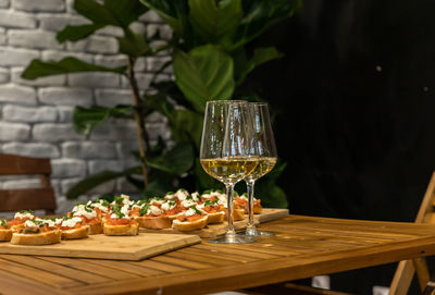 Toast or bruschetta with tomatoes, mozzarella and basil and two glasses with white wine.