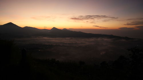 Scenic view of silhouette mountains against orange sky