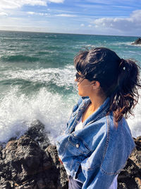 Rear view of woman standing at beach against sky