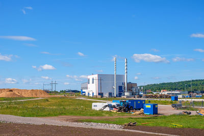 Factory on field against blue sky