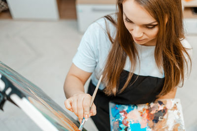 High angle view of beautiful woman painting on canvas
