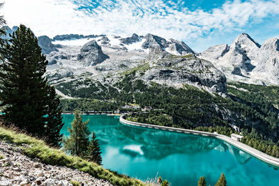 Scenic view of fedaia lake by mountains against sky