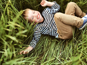 Portrait of a smiling boy lying on the green grass