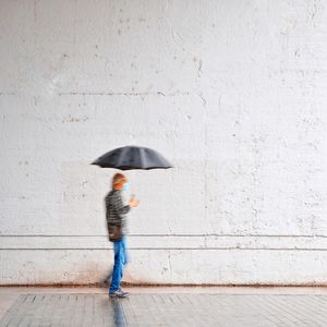Full length of woman walking on wet umbrella
