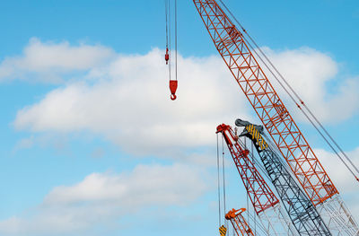 Low angle view of crane at construction site against sky