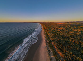 Aerial view of sea against clear sky during sunset