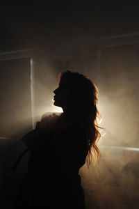 Side view of woman standing against sky during sunset