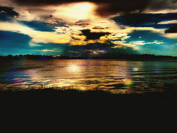 Scenic view of lake against dramatic sky during sunset