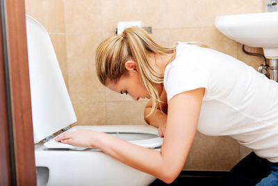 Side view of woman vomiting in bathroom at home