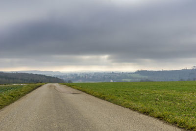 Road by field against sky