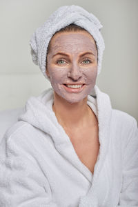 Close-up portrait of smiling woman with facial mask