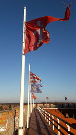 Low angle view of flags against clear blue sky