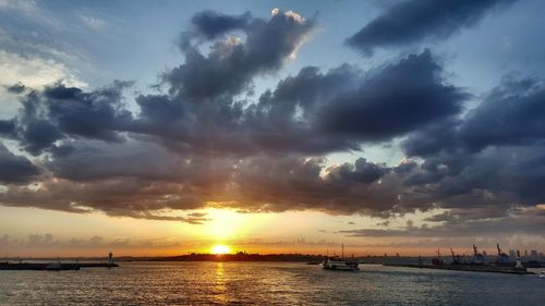 Scenic view of sea against dramatic sky during sunset