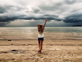 Rear view of woman walking on sand against sea at beach