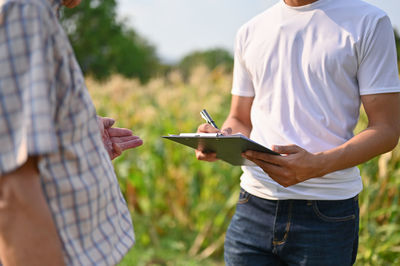 Midsection of man using digital tablet while standing outdoors