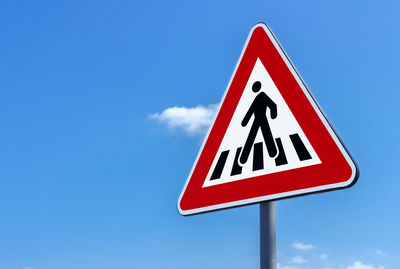 Low angle view of road sign against clear blue sky