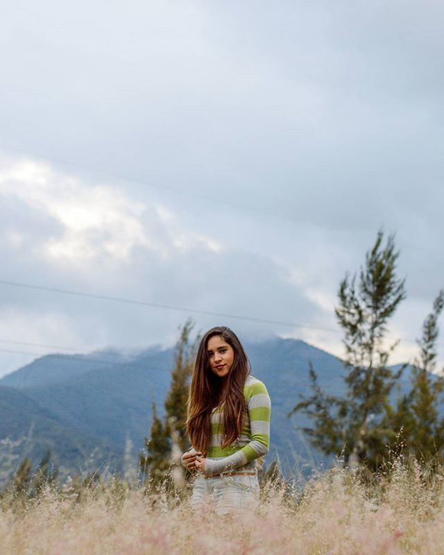 lifestyles, leisure activity, sky, young adult, mountain, casual clothing, person, looking at camera, portrait, standing, landscape, front view, smiling, cloud - sky, tranquility, nature, tranquil scene, young women