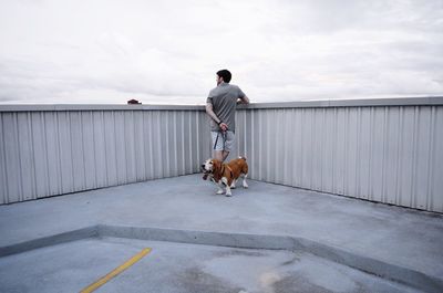 Man standing on railing against sky