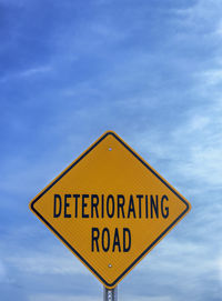 Low angle view of road sign against blue sky