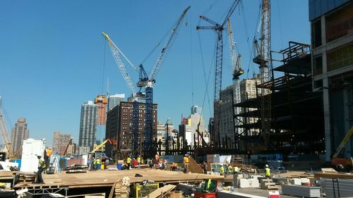 Workers at construction site against clear sky