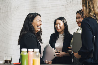 Cheerful female professionals networking in conference meeting at office