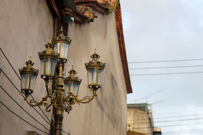 Low angle view of street light by building against the sky