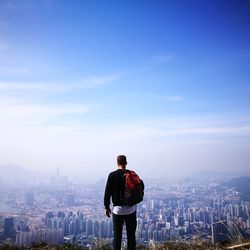 Rear view of man standing on city against sky