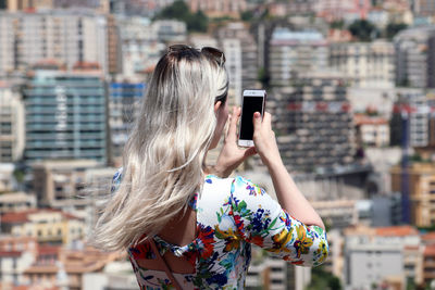 Man photographing with mobile phone in city