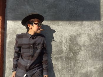 Teenage boy smoking cigar against wall