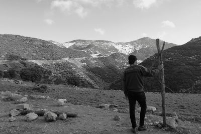 Rear view of man standing on mountain against sky