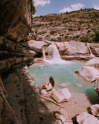 Woman sitting on rock formation in water