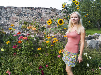 Young woman standing by flowers