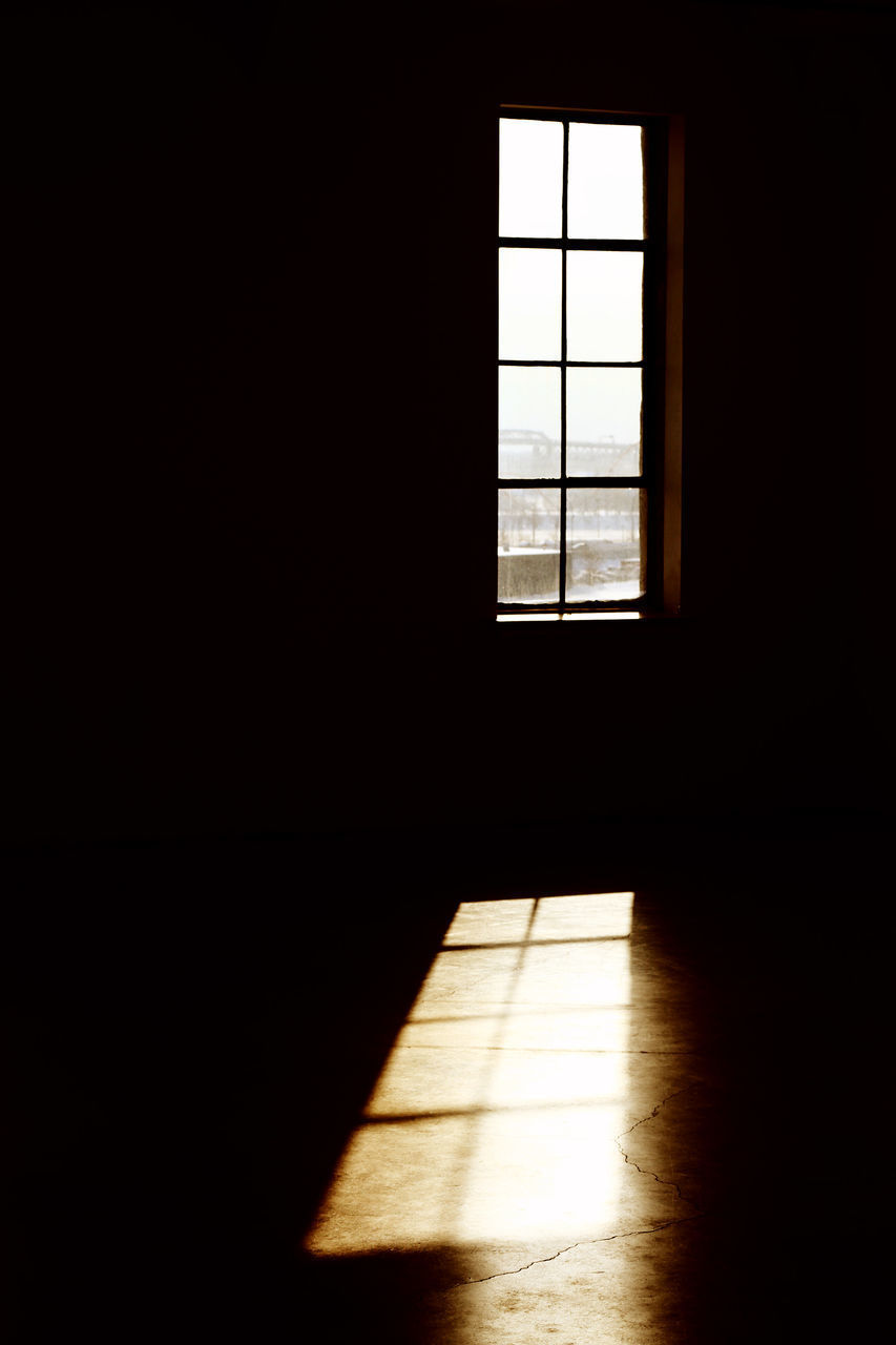 SUNLIGHT STREAMING THROUGH WINDOW ON FLOOR IN DARK ROOM