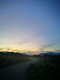 Road by landscape against sky during sunset