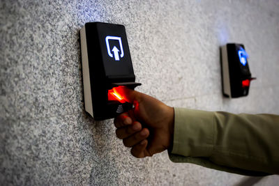 Midsection of man holding mobile phone against wall