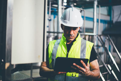 Portrait of man using digital tablet while standing in factory