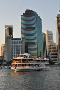 Modern buildings by river against sky in city