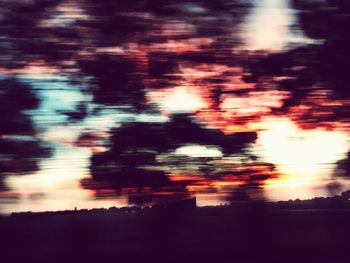 Defocused image of silhouette trees against sky during sunset
