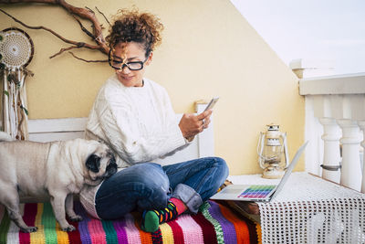 Mature woman using phone while sitting at home