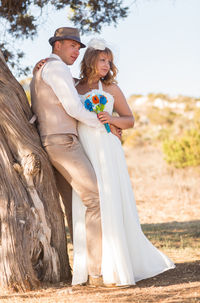 Side view of couple standing by tree